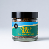 Jar of chili salt with a black lid on a light gray background