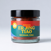 Jar of Er Jing Tiao powder with colorful label on a light gray background